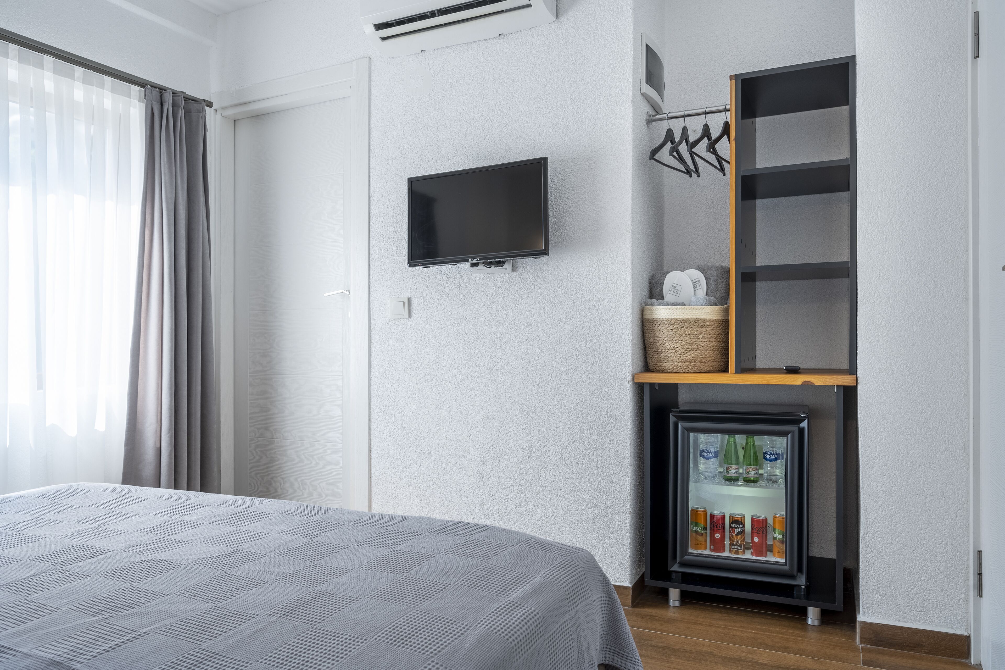 Quarto com cama, televisão, minibar e guarda-roupa.