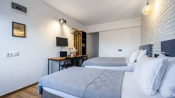 A modern hotel room with two beds, a desk, a chair, a TV, and a wardrobe.