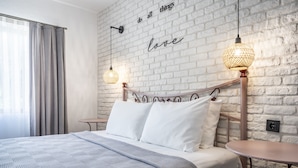 A modern hotel room with a brick wall, a bed with white linens, two bedside tables, and a wall-mounted light fixture. - The Poyz Hotel Bodrum (Bodrum)