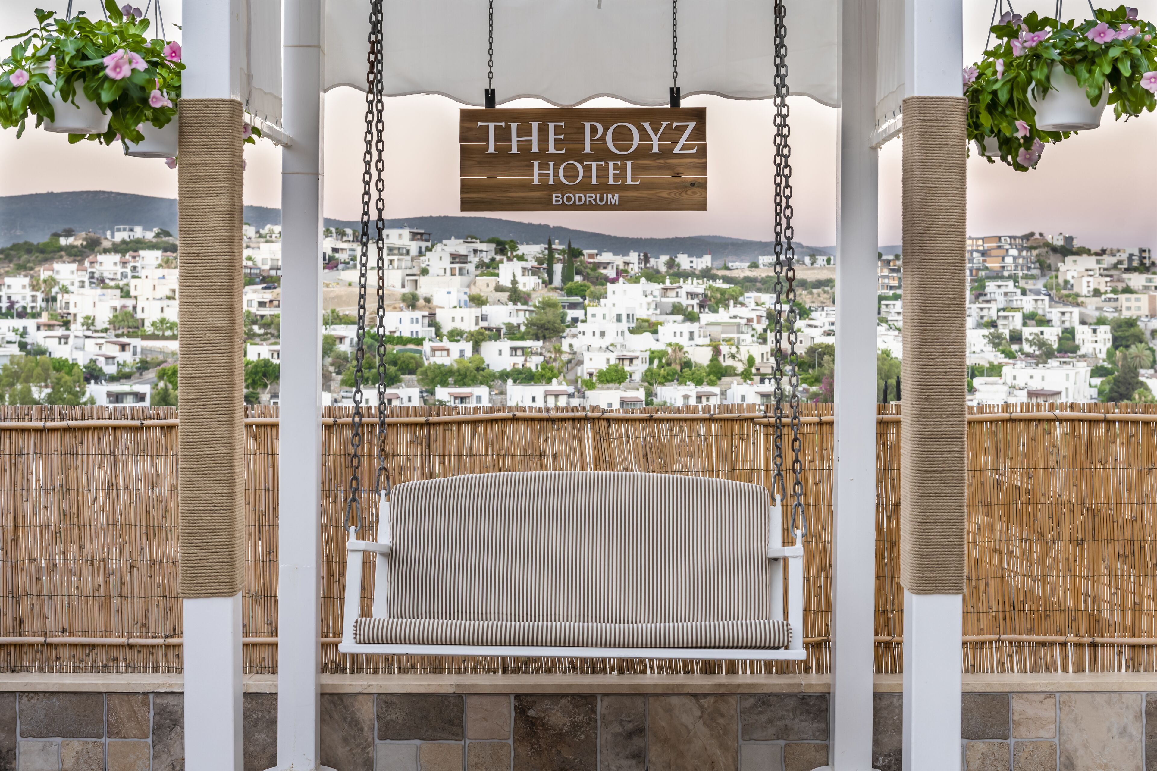 A wicker swing chair in a covered outdoor area with a view of a town in the background.