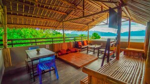 An outdoor seating area with bamboo furniture, a table, and a view of lush greenery and mountains. - The Ridge Coron (Coron)