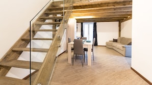 A modern interior with a wooden staircase, a dining area, and a sofa. - Le suites del duomo house (Catania)