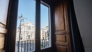 A view from a room with a large window overlooking a historic building with classical architecture. - Le suites del duomo house (Catania)