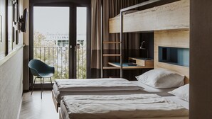 Habitación de hotel con dos camas, una silla y un escritorio con computadora.