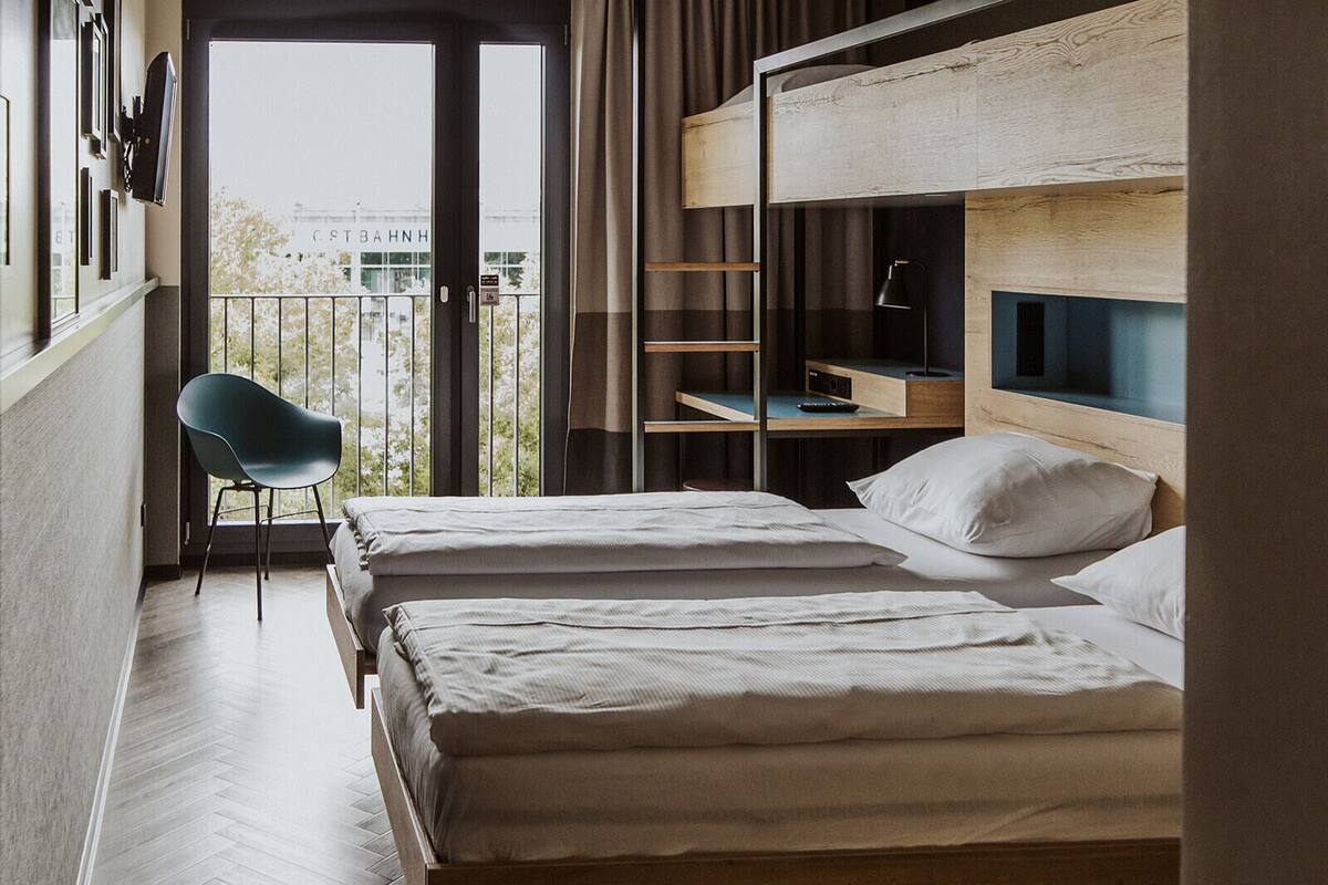 A hotel room with two beds, a chair, and a desk with a computer.