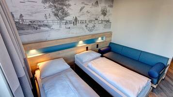 Una habitación con dos camas individuales y un sofá cama.