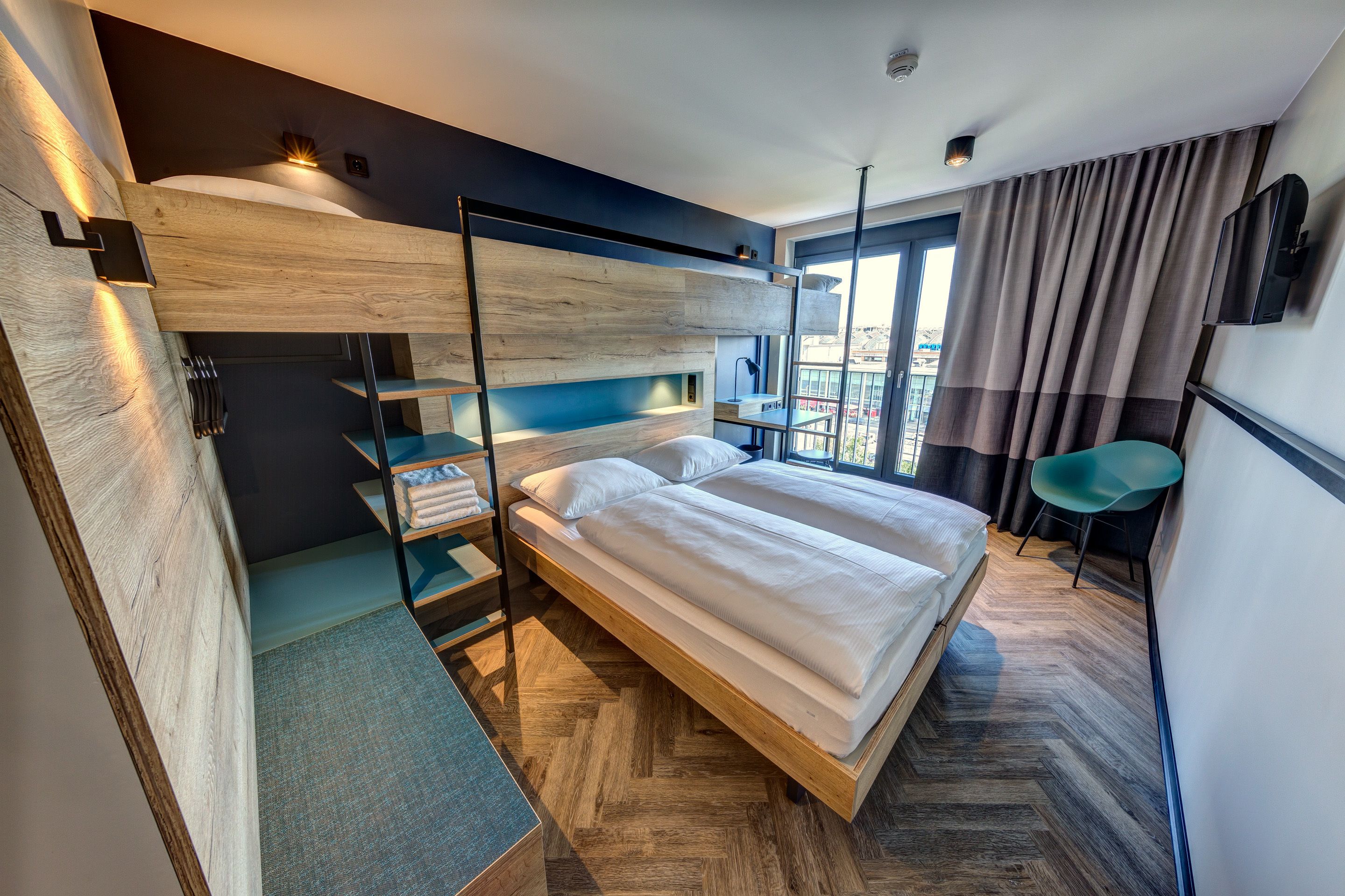 Ein modernes Hotelzimmer mit Stockbett, Schreibtisch und Stuhl.