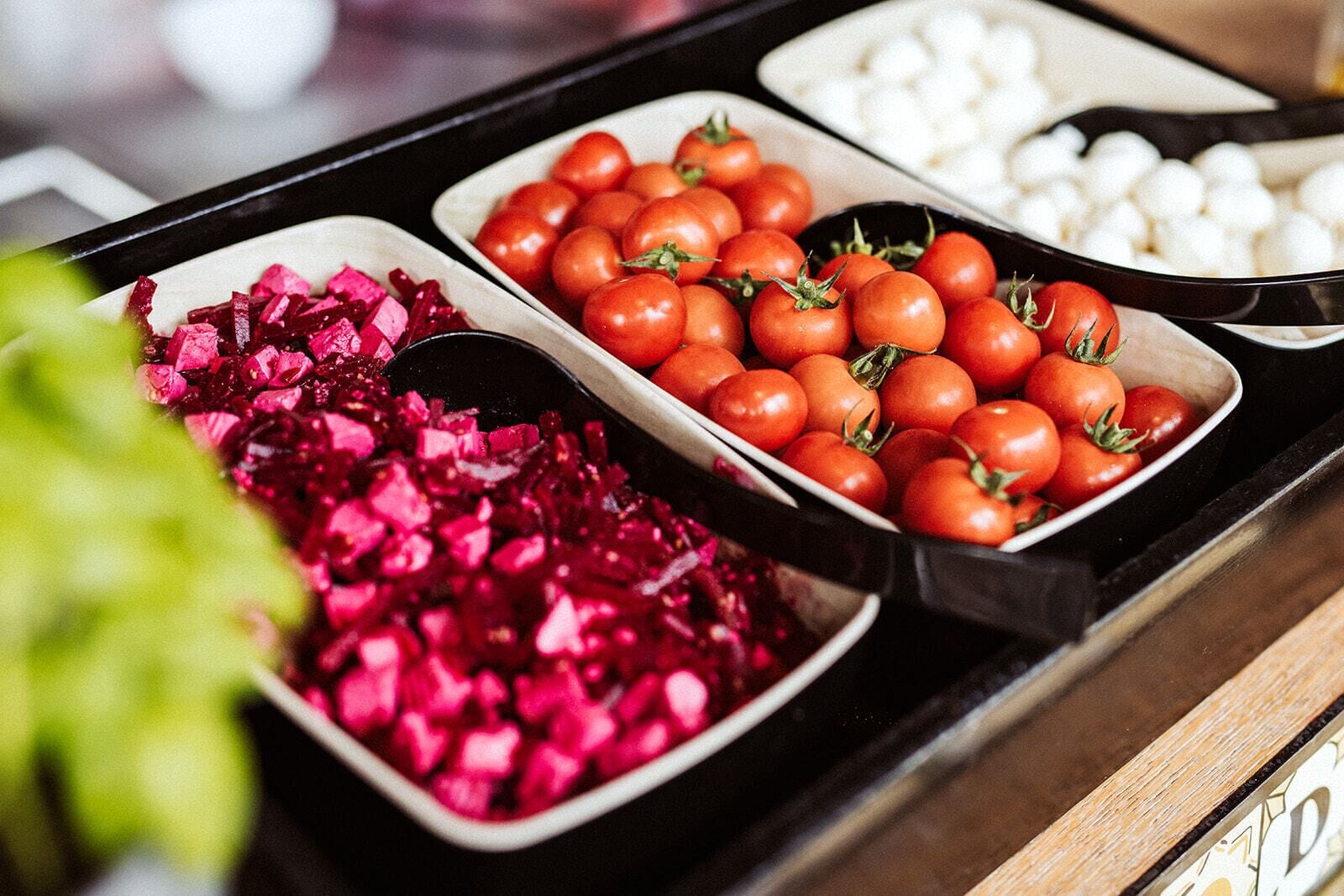 A buffet with various food items including tomatoes, beets, and cheese.