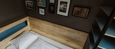 A small, single-bed room with a wooden headboard and a blue shelf unit.