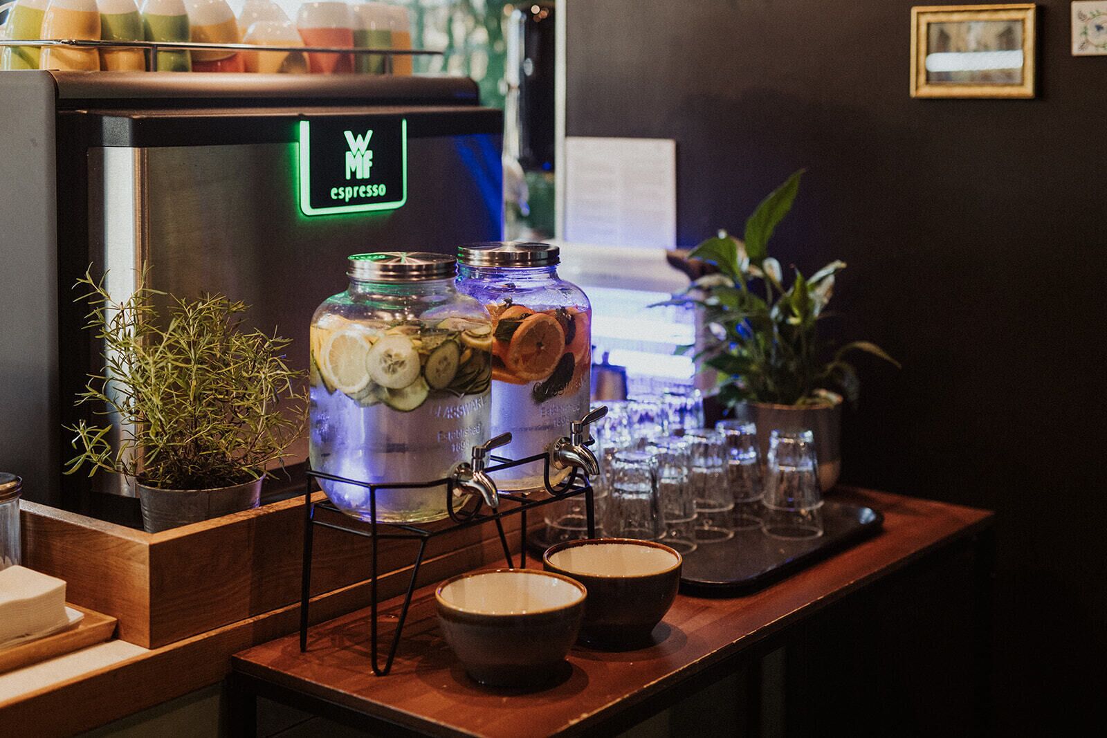 A bar area with a coffee machine labeled 'WM espresso' and two large jars of pickled vegetables on a metal stand.