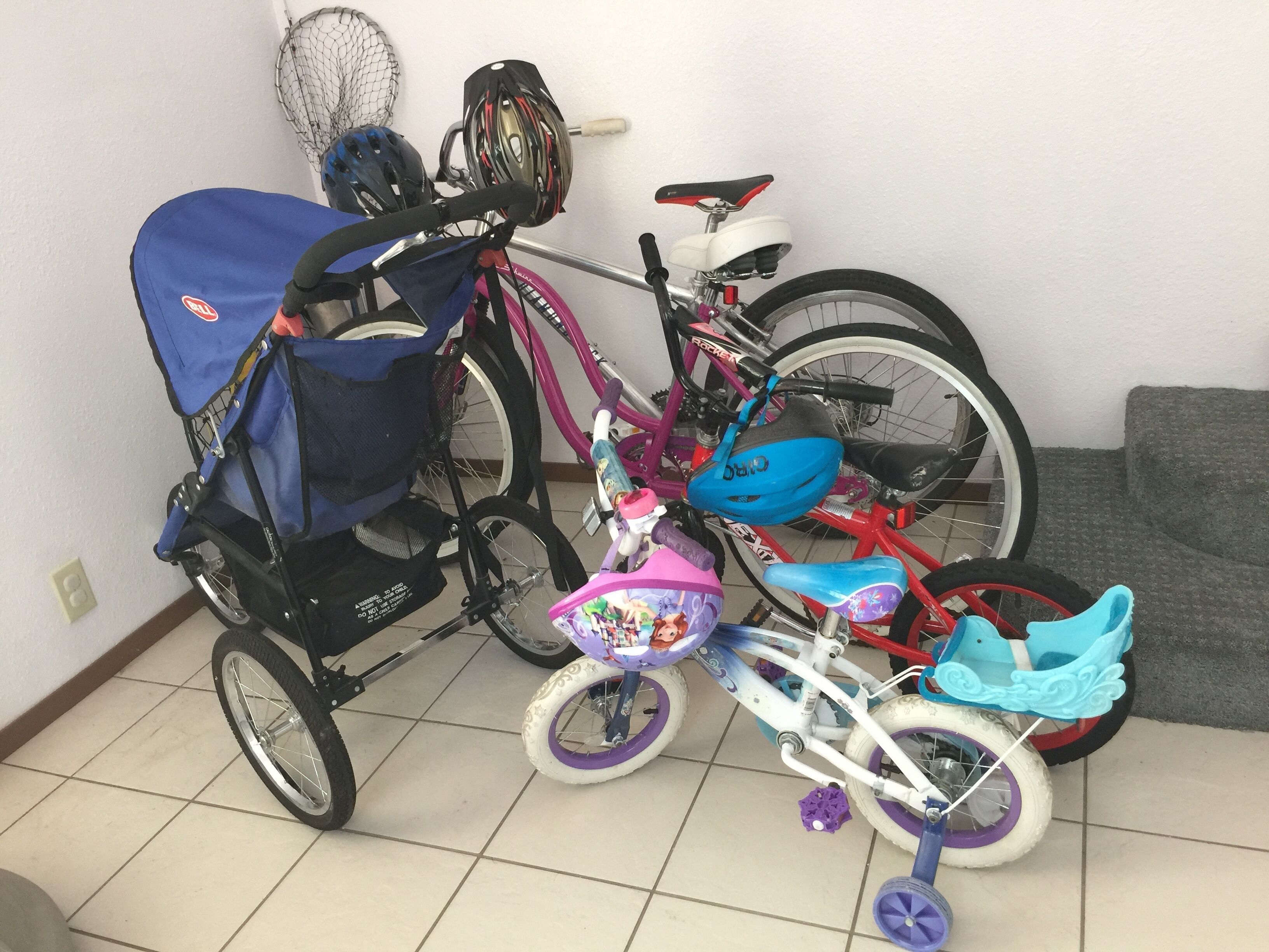 Et værelse med flisegulv, en grå sofa og cykler.