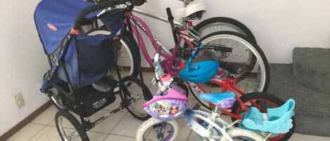 Et værelse med flisegulv, en grå sofa og cykler.