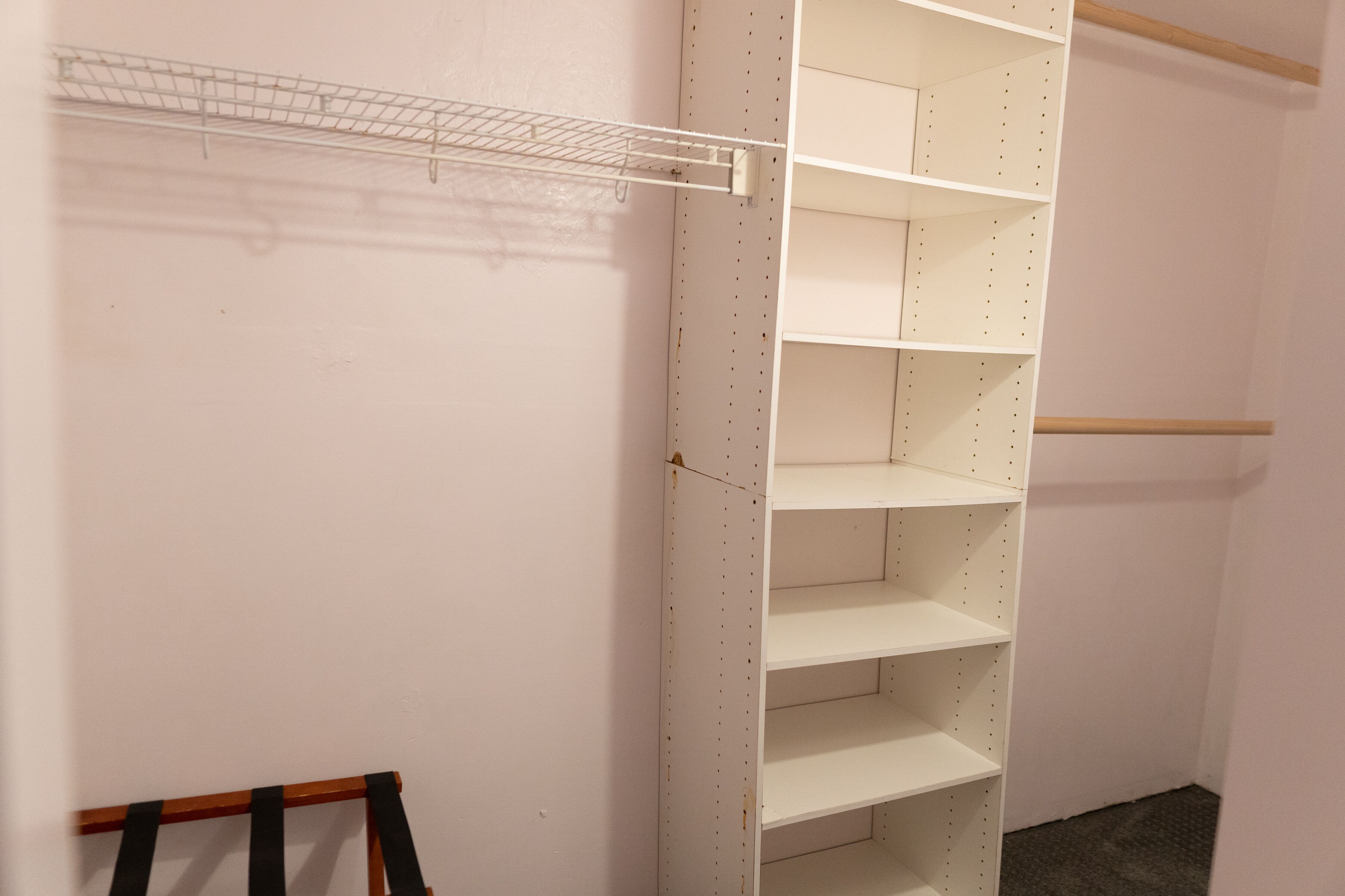 A storage closet with multiple shelves and a hanging rack.
