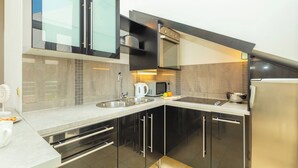 Een moderne keuken met zwarte kastjes, roestvrijstalen apparatuur en een magnetron.