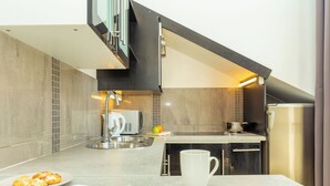 Een moderne keuken met een ingebouwde magnetron, een waterkoker en een spoelbak. Op het aanrecht ligt een tijdschrift en staat een witte mok.