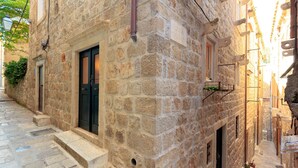 Un edificio de piedra estrecho con una puerta negra y una ventana pequeña.