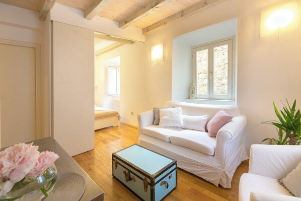 A room with a white sofa, a blue trunk, and a potted plant.