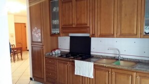 Une cuisine avec des meubles de rangement en bois, une cuisinière à gaz, un évier et un dosseret carrelé.