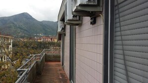 Un balcon avec vue sur les montagnes, un mur recouvert de carreaux et des unités de climatisation.