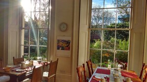 A dining room with a large table set for four, surrounded by wooden chairs. There is a clock on the wall and a framed picture above the table. - Temple Lodge Club (London)