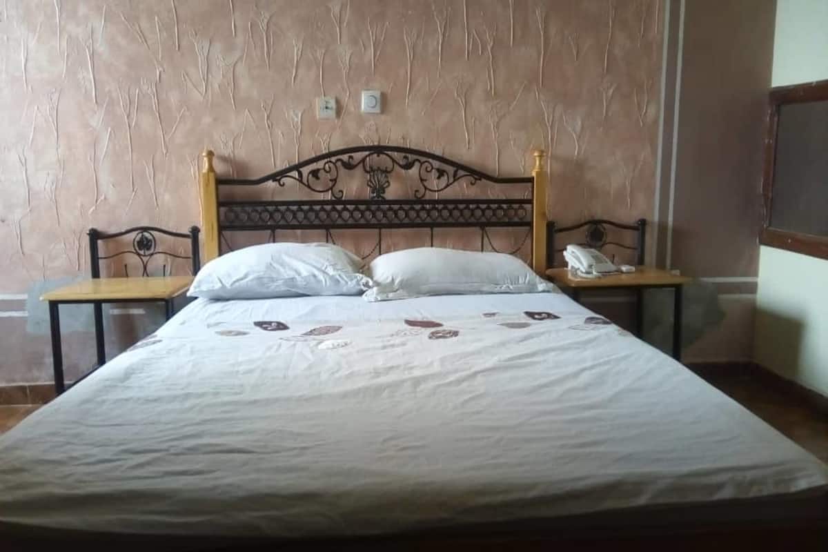 A bed with a headboard, two bedside tables, and a wall with a textured pattern.
