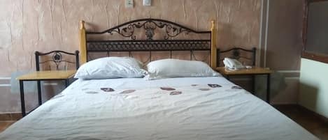 A bed with a headboard, two bedside tables, and a wall with a textured pattern.
