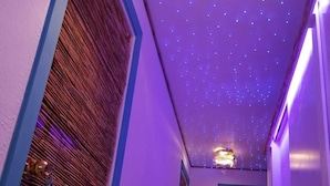 Un couloir avec un plafond étoilé, des portes en bois et un luminaire décoratif.