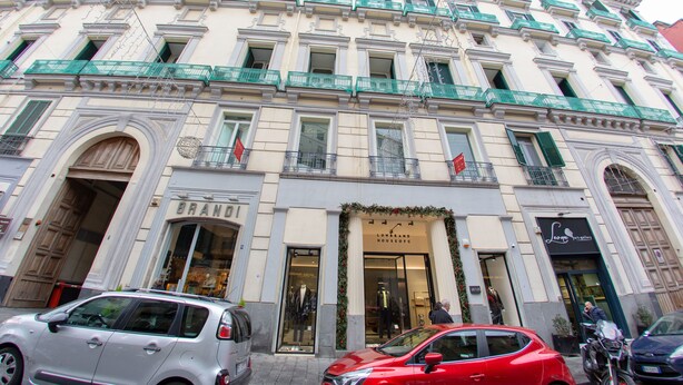 A multi-story building with a classic architectural style, featuring a ground-level entrance with a large arched doorway and a sign that reads "BRAND". - Leone Camere D'Autore (Naples)