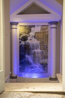 Una fontana con cascata e illuminazione blu, incorniciata da colonne.