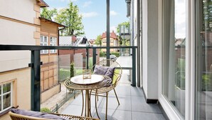 A balcony with a round table and wicker chairs, overlooking a street with buildings and trees. - Monte Carlo Luxury Suites with Parking by Lion Apartments Sopot (Sopot)