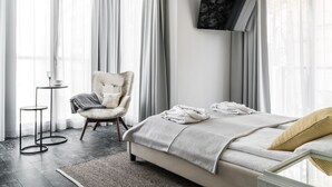 A modern bedroom with a bed, a chair, a TV, and a small table. - Monte Carlo Luxury Suites with Parking by Lion Apartments Sopot (Sopot)