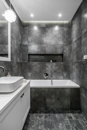 Une salle de bain moderne avec une baignoire sur pieds, un grand miroir et un meuble-lavabo blanc.
