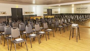 A conference room with rows of chairs, a podium, and a wall with a sign.