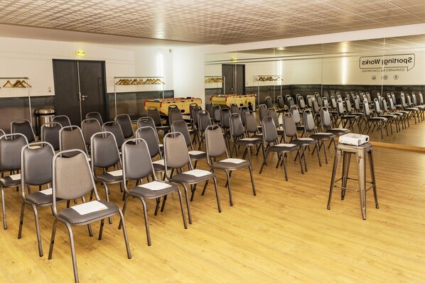 Un salón de conferencias con filas de sillas, un atril y una pared con un cartel.