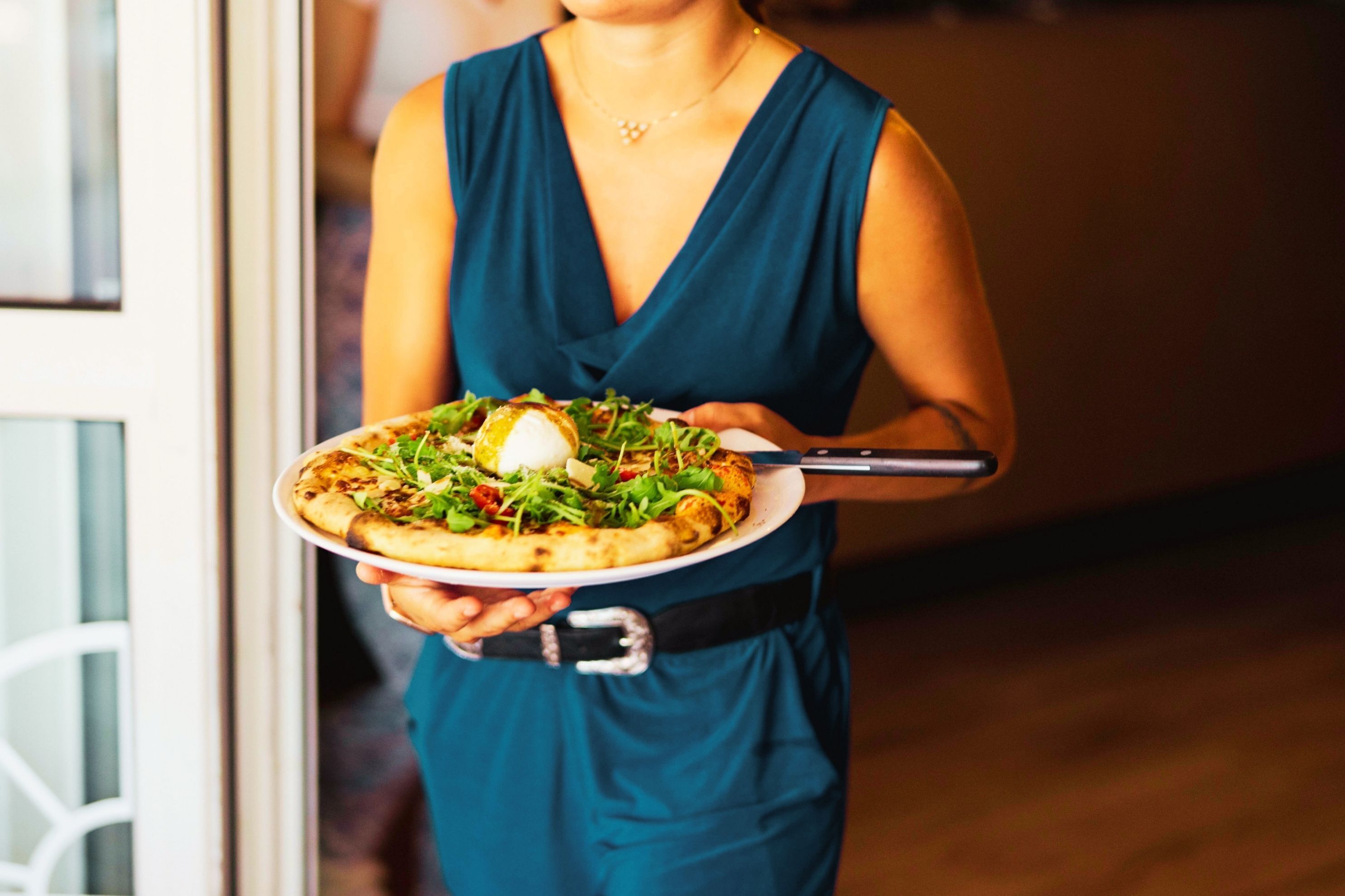 Une personne tenant une assiette avec une pizza et une fourchette.