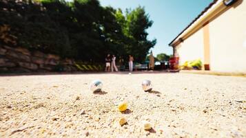 A close-up of a sandy surface with two shiny balls and a yellow ball.
