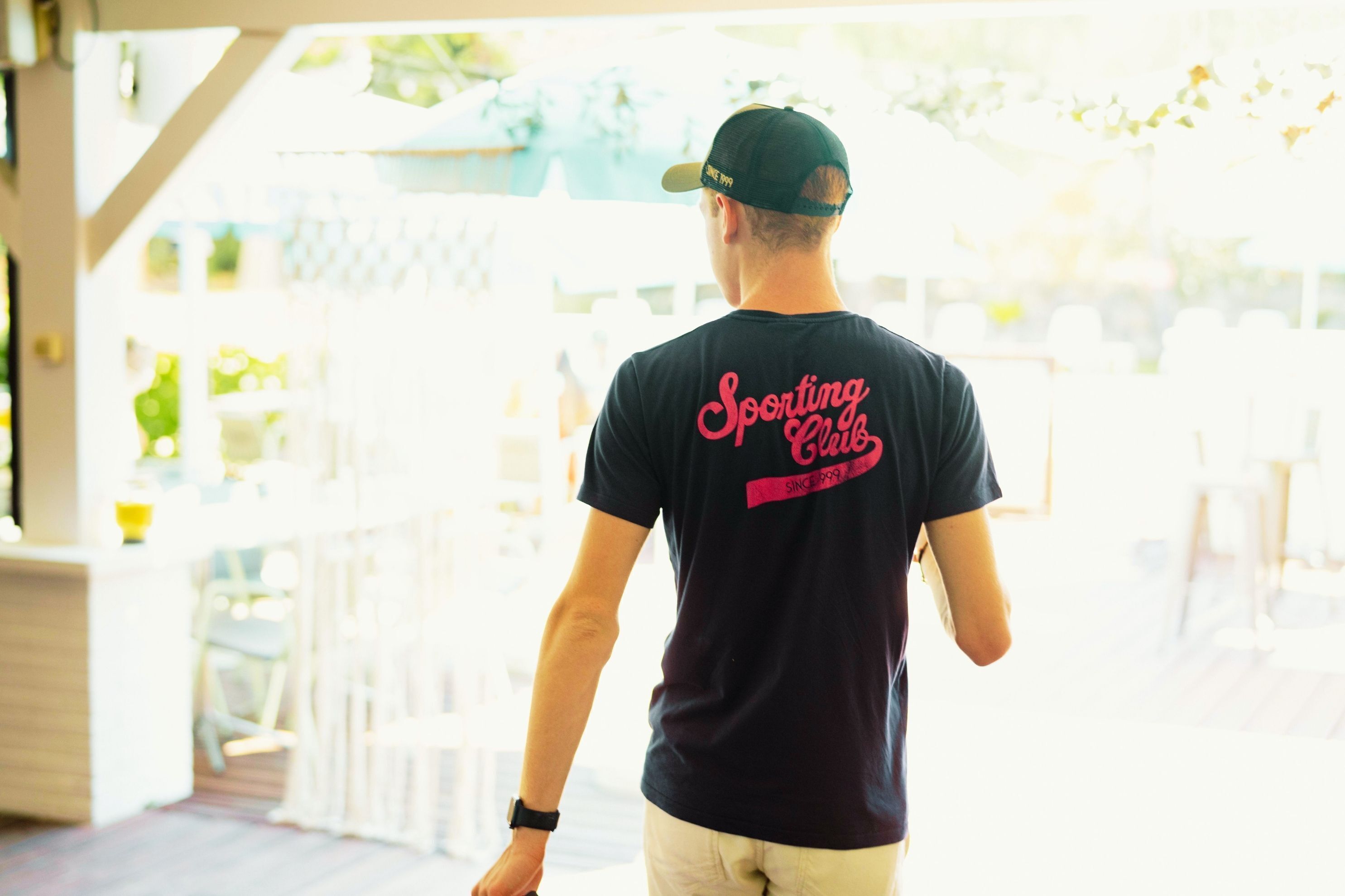 A person walking inside a building with a sign on the wall that reads "Sporting Club".