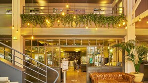 Un espacio interior de varios niveles con una escalera, un sofá de cuero y una zona de bar con asientos visibles y plantas.
