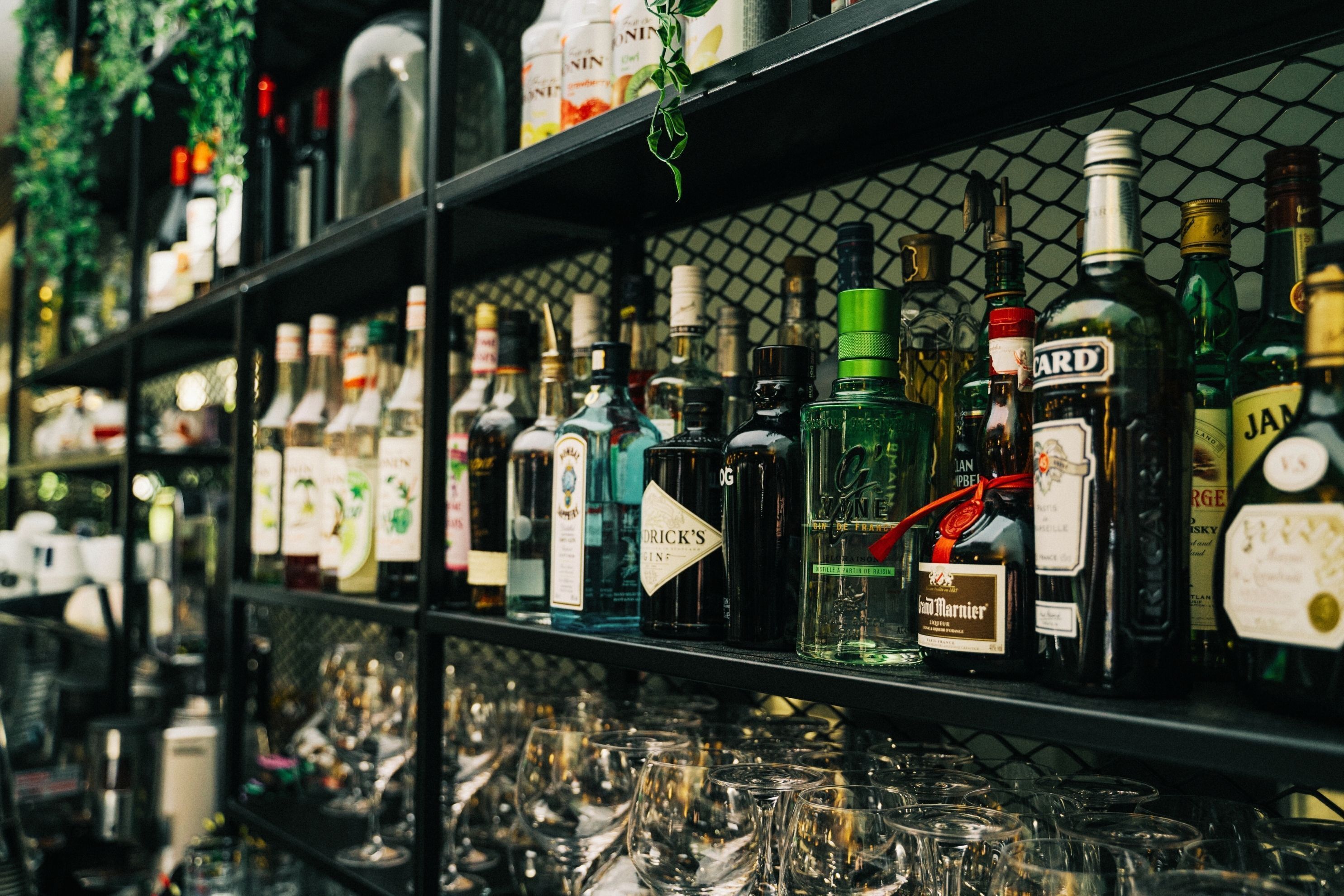 A bar shelf stocked with various liquor bottles and glasses.