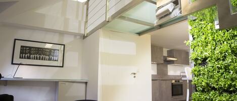 A modern kitchen with a built-in oven, a dining area with a round table and chairs, and a staircase leading to an upper level.