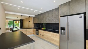 Une cuisine moderne dotée d’un grand îlot central, d’appareils électroménagers intégrés et donnant sur l’espace repas.