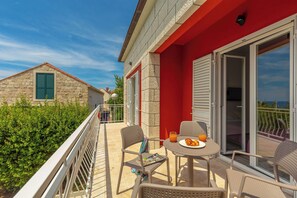 A balcony with a table set for two, a red building, and a stone house in the background. - Hedera Estate, Villa Hedera V (Dubrovnik)