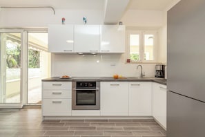 Une cuisine moderne avec des armoires blanches, un four en acier inoxydable et un réfrigérateur.