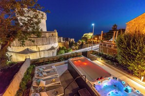A spa area with a hot tub and lounge chairs, surrounded by stone walls and greenery. - Hedera Estate, Villa Hedera V (Dubrovnik)