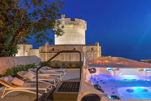 Une structure ressemblant à un château, dotée d’une tour ronde, de fauteuils de salon pour l’extérieur et d’un jacuzzi avec jets illuminés.