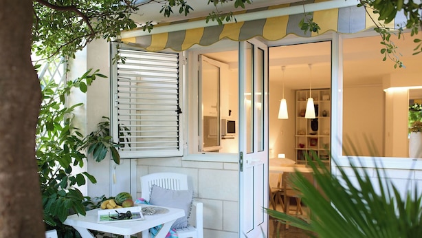 Une terrasse avec une table, des chaises et une fenêtre équipée de stores.