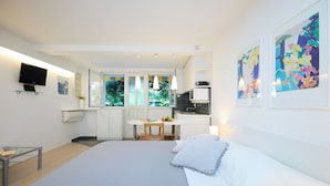 Une chambre d’hôtel moderne équipée d’un grand lit, d’un bureau, d’une kitchenette et d’une télévision.