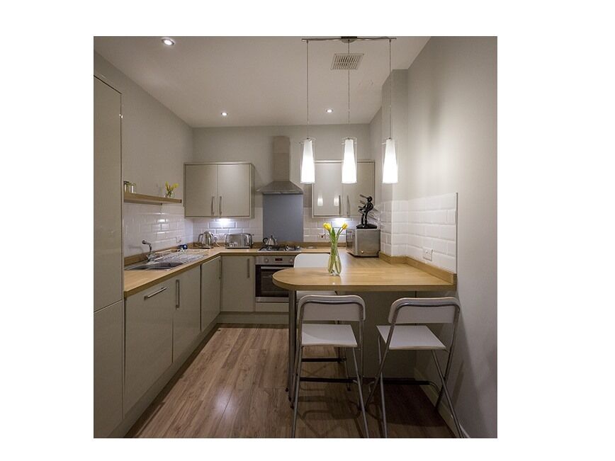 A modern kitchen with a central island, white cabinetry, and pendant lighting.