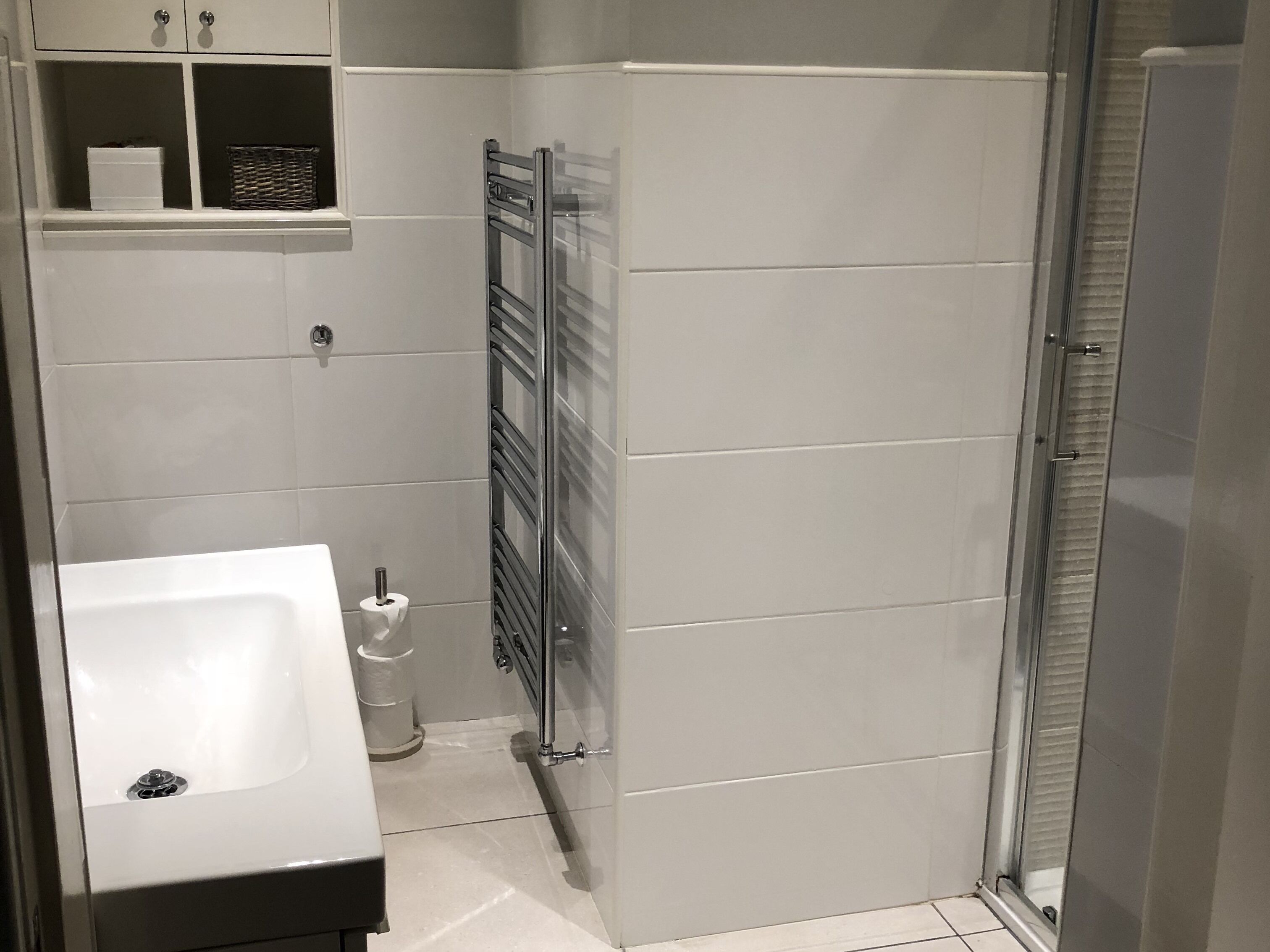 Um banheiro moderno com pia branca, vaso sanitário e área de chuveiro.