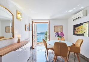 A modern interior with a dining area, a large mirror, and a view through an open door.